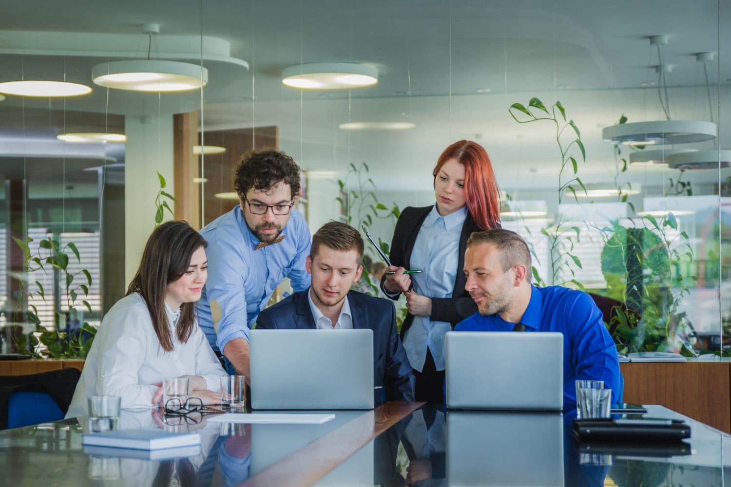Colleagues collaborating at a desk, focused on a laptop.